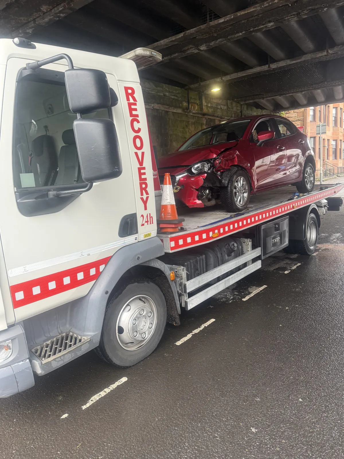Accident-damaged red car on recovery truck